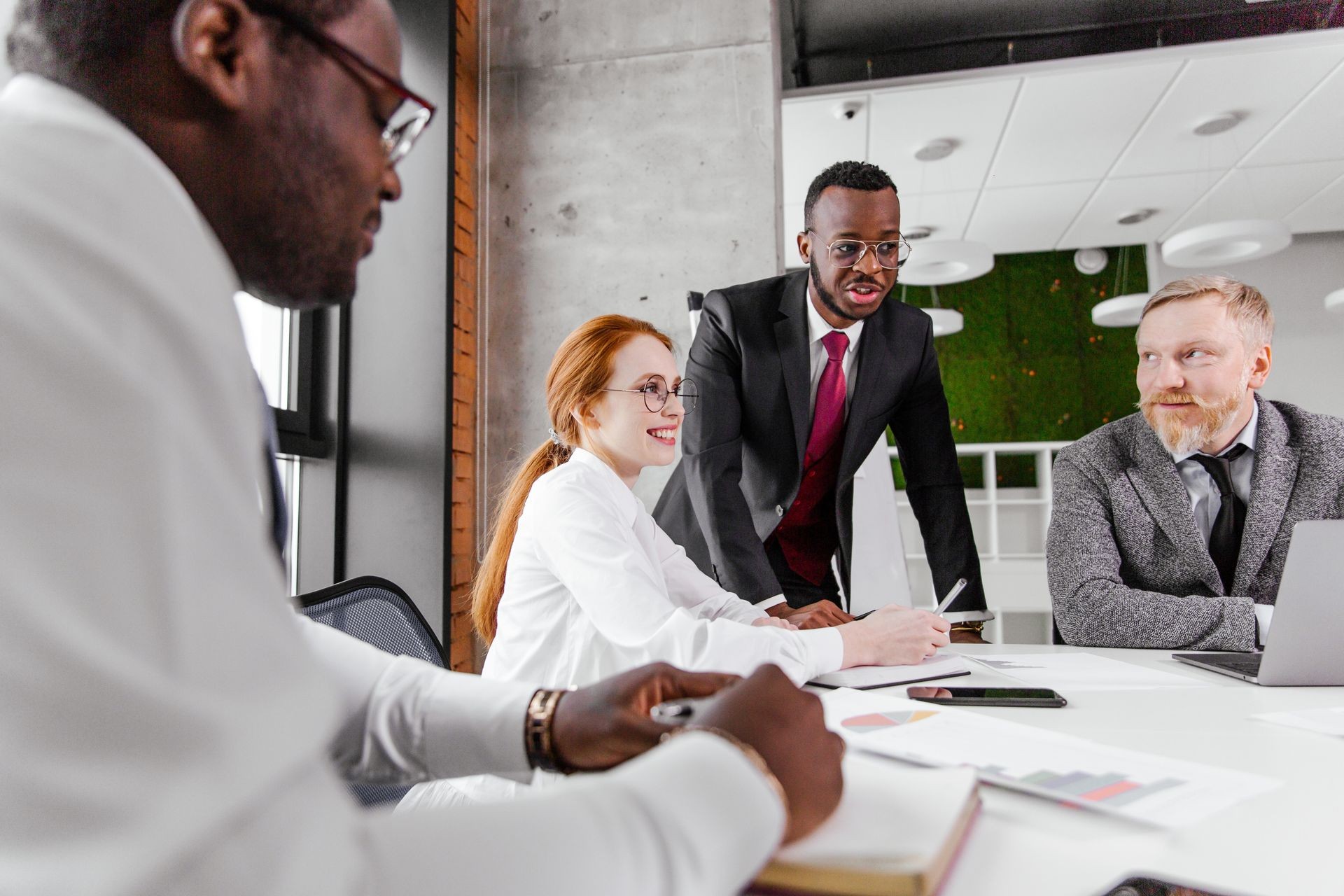 Corporate business team working in the office space for the development of the enterprise. African partners conclude a contract with a red-haired beautiful girl and an adult man with gray hair